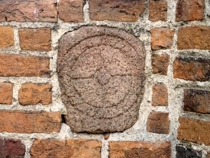 Symbol wykuty w kamieniu wmurowanym w ścianę wieży kościoła farnego.<br>Prawdopodobnie  przedchrześcijański  symbol solarny.